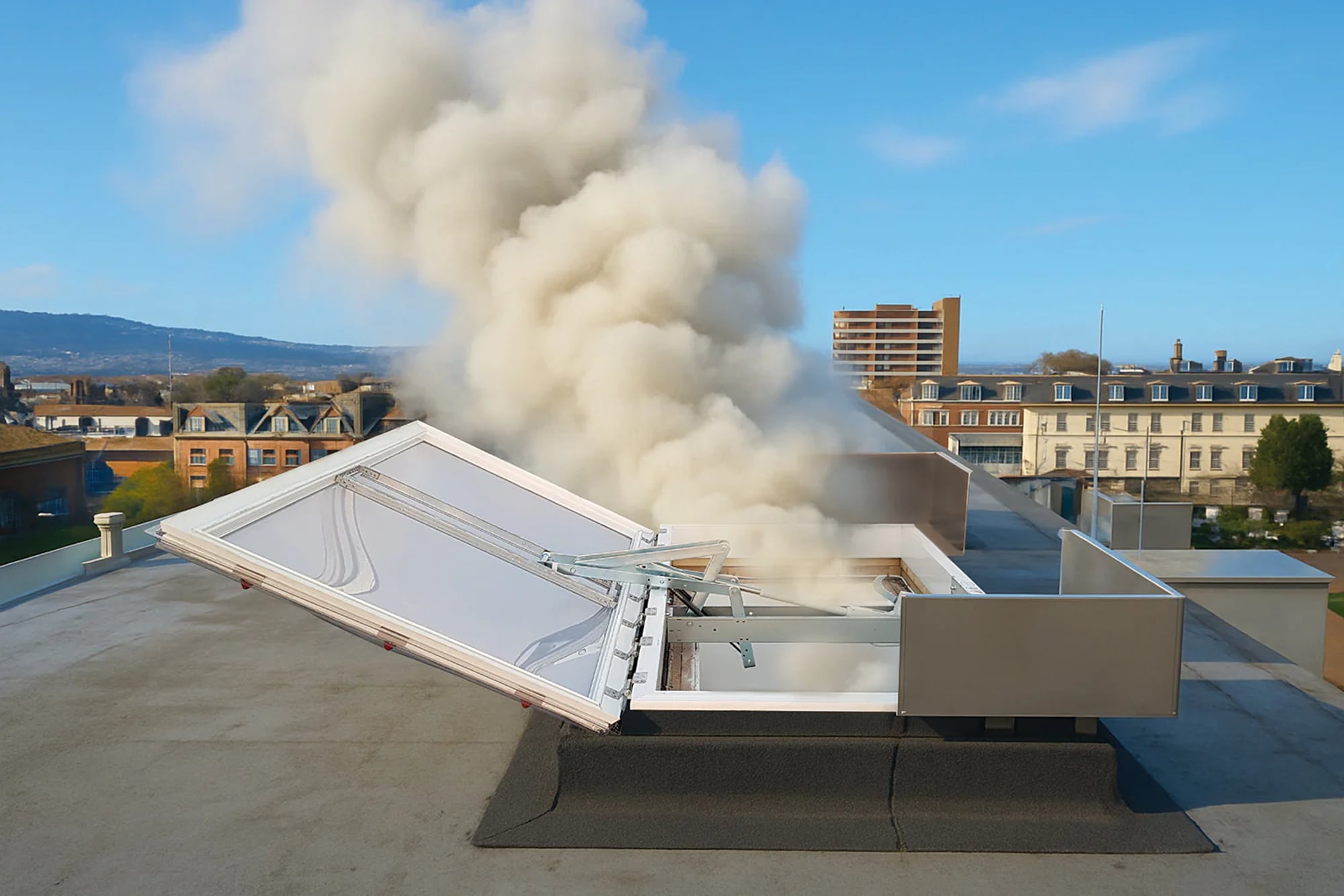 Rooftop AOV smoke vent open and discharging smoke clear of the building during a live test